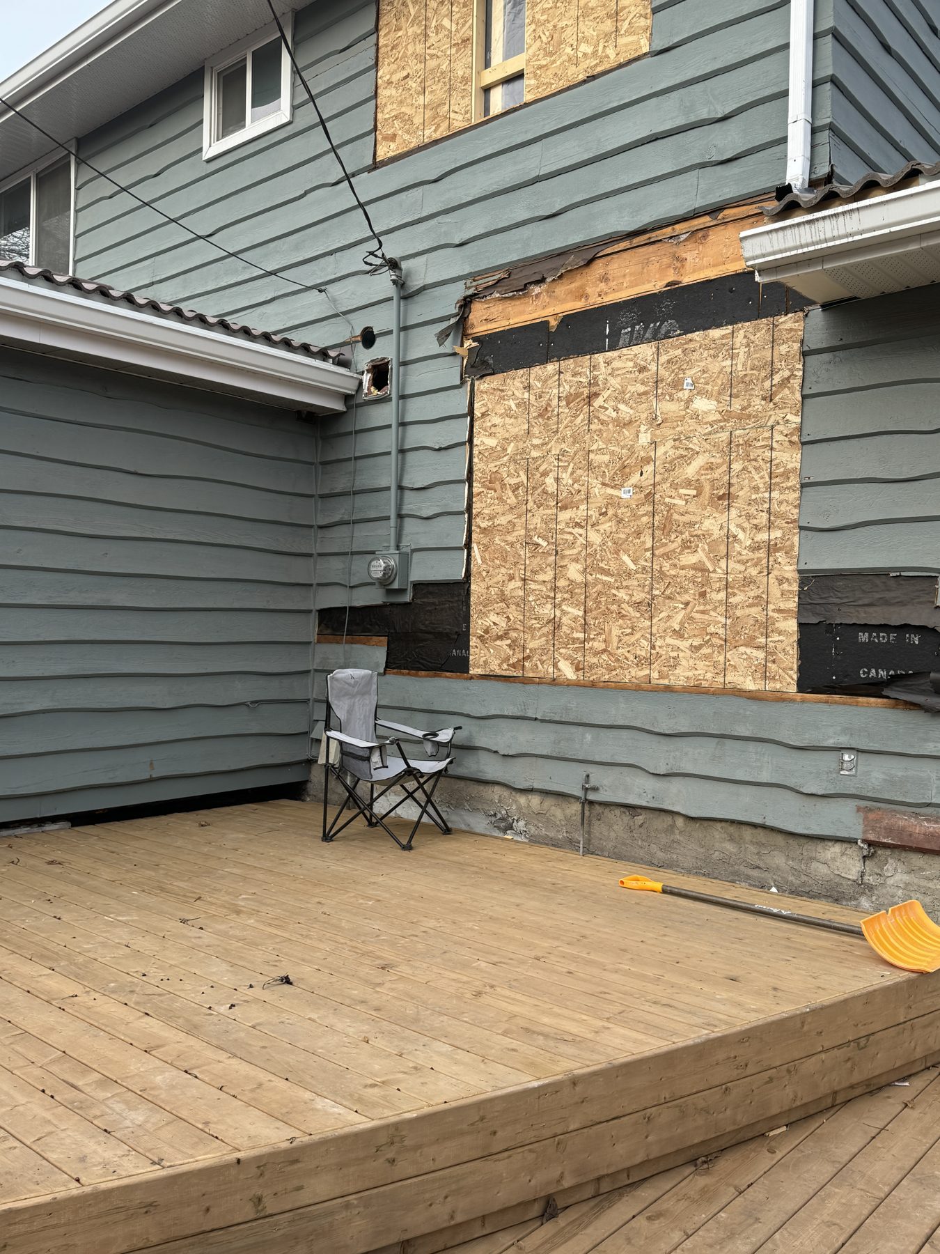 House exterior renovation with plywood-covered windows and unfinished deck — 188 Lake Adams Crescent SE, Calgary