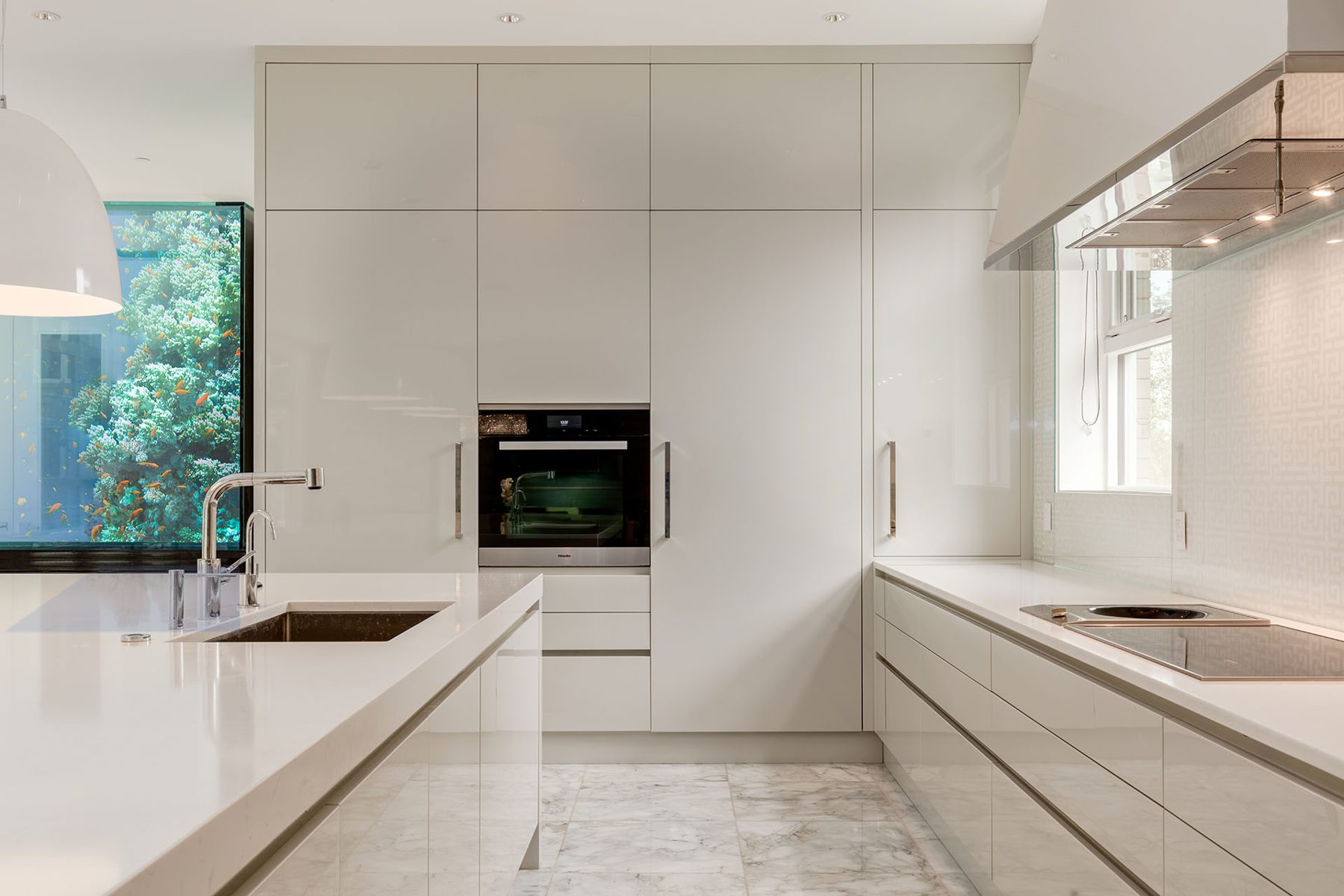 Modern white kitchen island with sink and custom aquarium wall — Germania