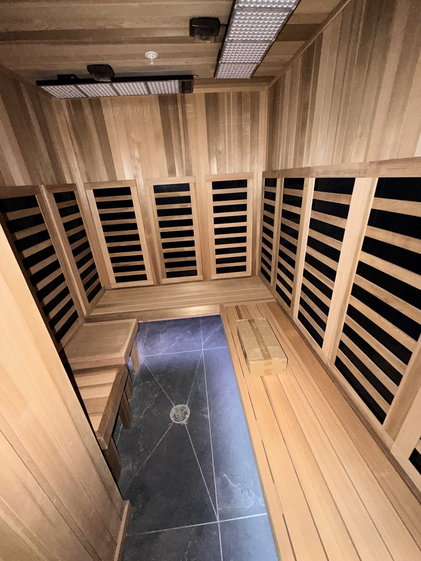Wooden sauna interior with benches, black panel heaters, and tiled floor — Cedar Steam and Spa (Trinity Hills)