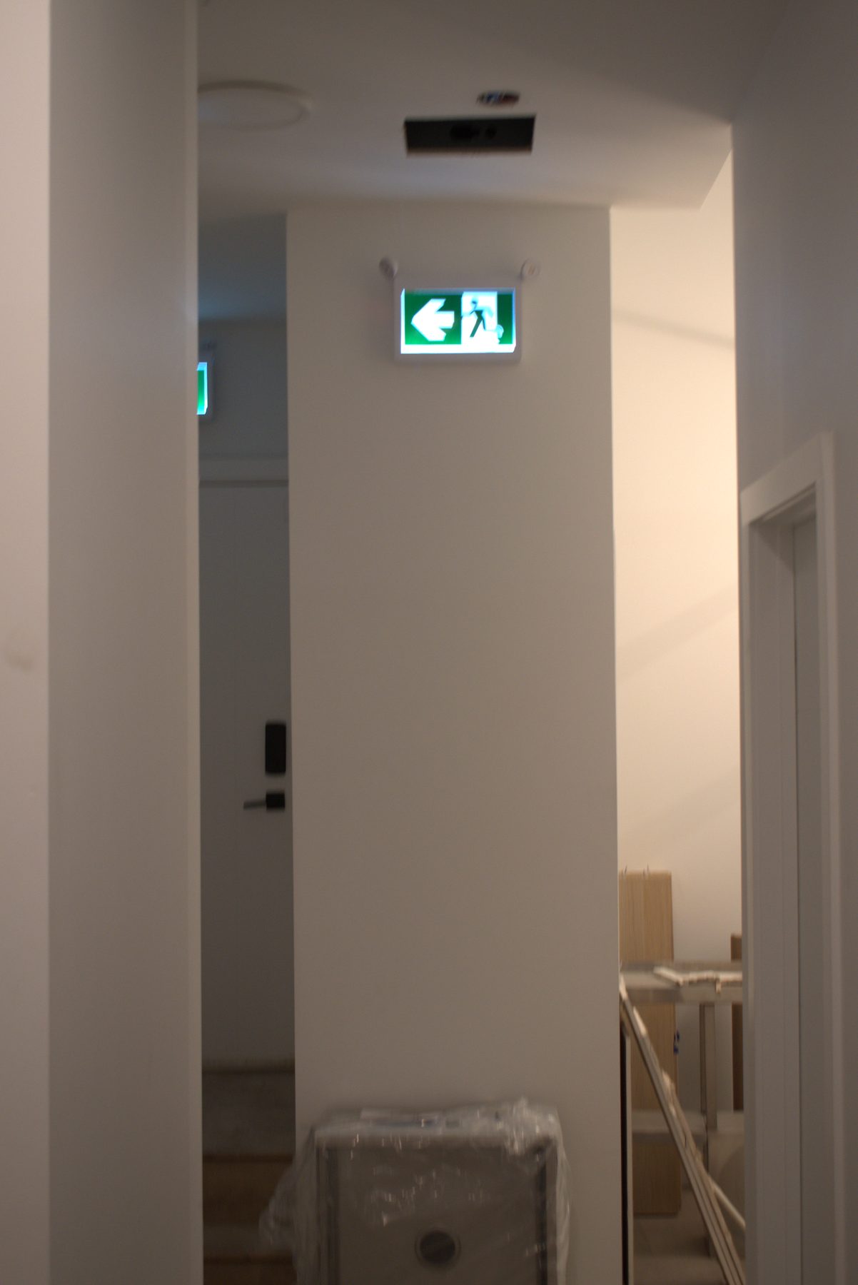 Hallway renovation with exit sign, door, and covered item — Big Buns (Bowness)