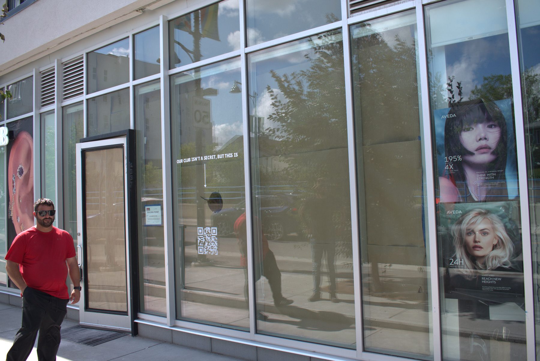 Man in red shirt, glass storefront, construction permit, hair ads — Big Buns (Bowness)