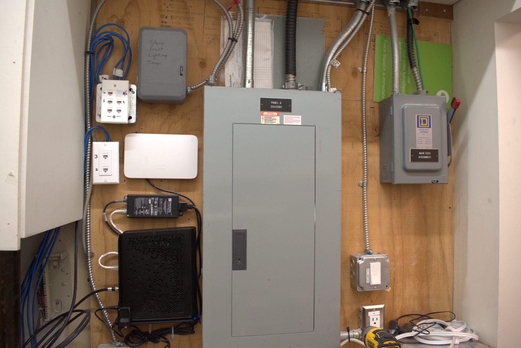 Electrical panel, router, timer, and Cisco wireless access point installed on plywood — Leela Spa (Bankers Hall)