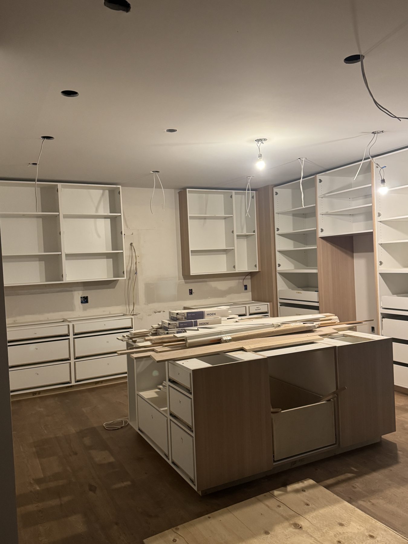 Kitchen renovation with installed cabinets, island base, and unfinished ceiling fixtures — 14 Lochend Drive, Cochrane