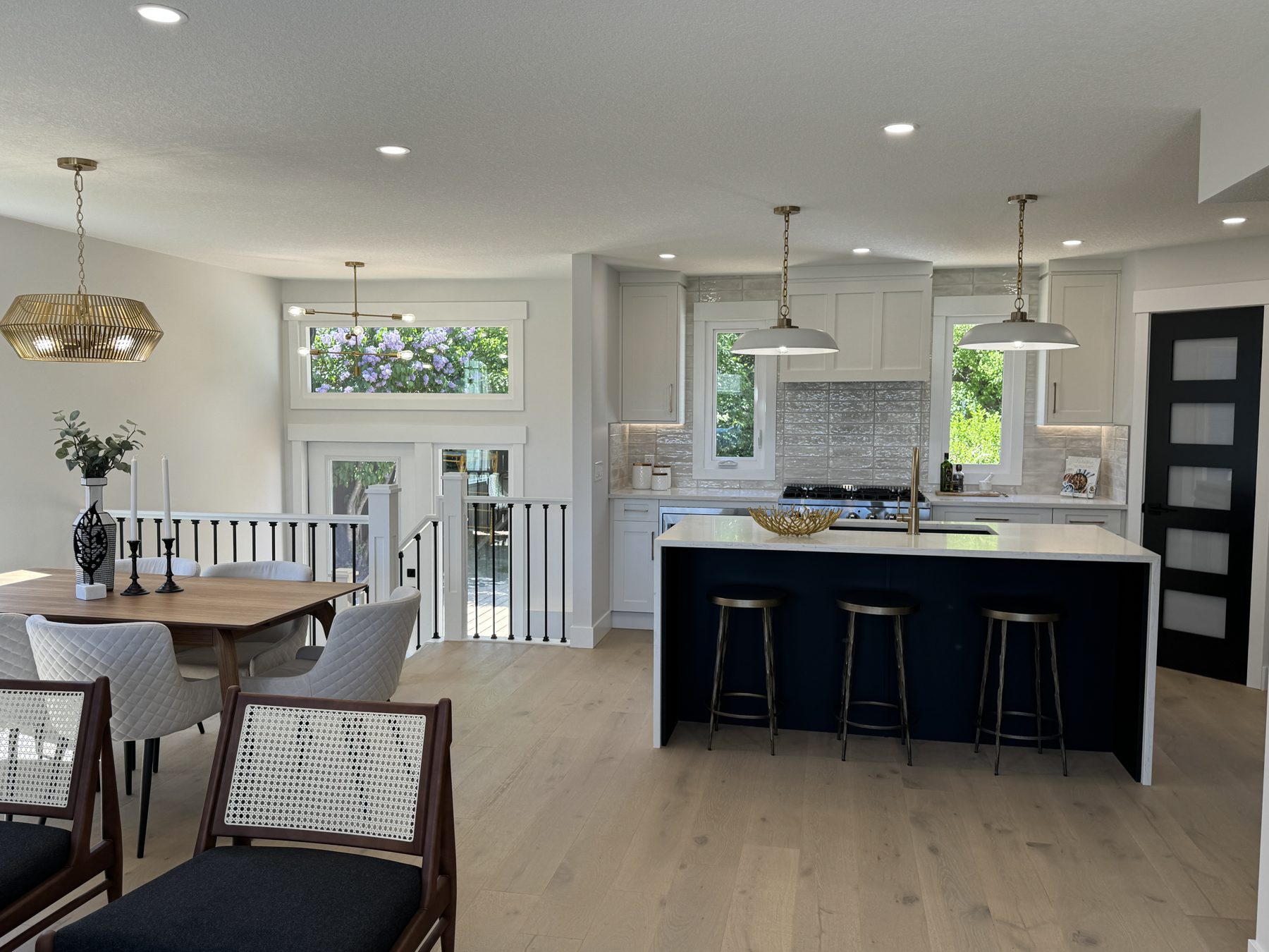 Modern kitchen and dining room with navy island, white cabinets, and light wood floors — Lake Bonavista