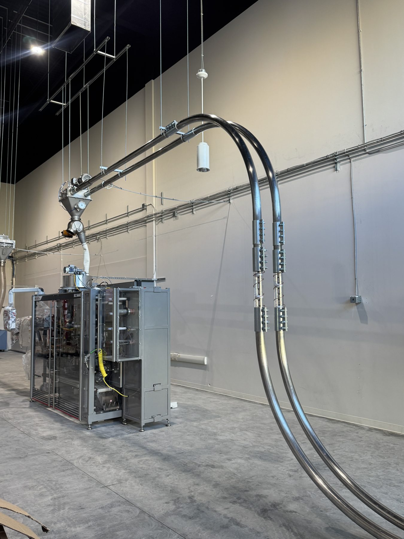 Industrial packaging machine with overhead metal tubing and conduits — Eight Ounce Coffee
