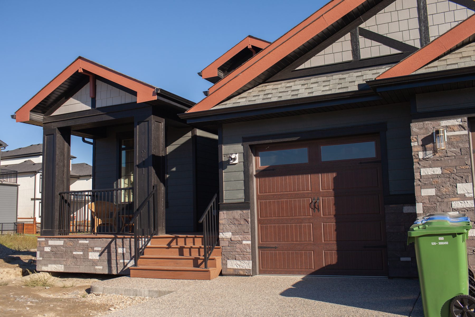 New house exterior with brown garage door, stone accents, and porch — 211 Blackstone Rd by Onsite Contracting Services
