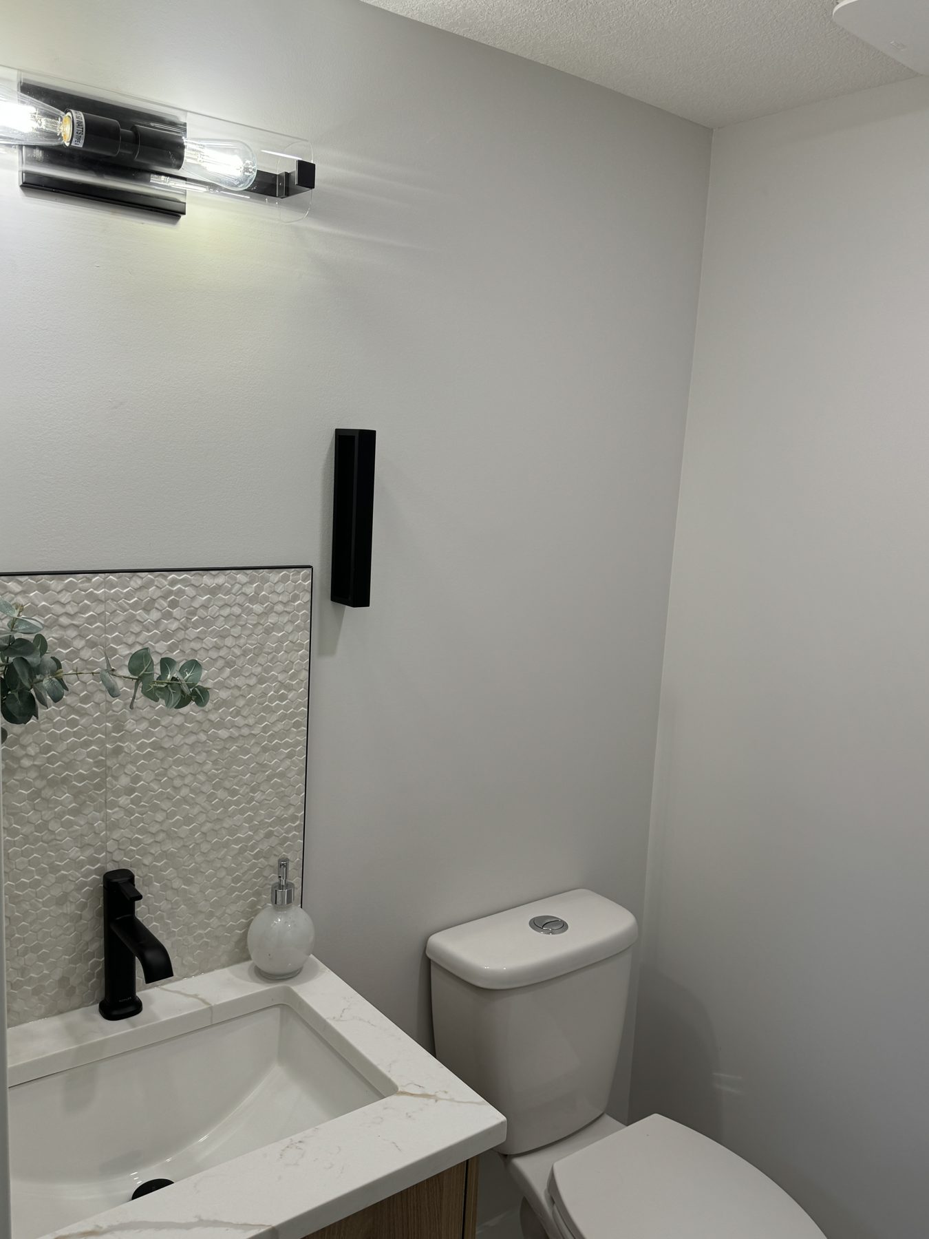 Modern bathroom renovation with mosaic tile, black faucet, and toilet — Lake Bonavista