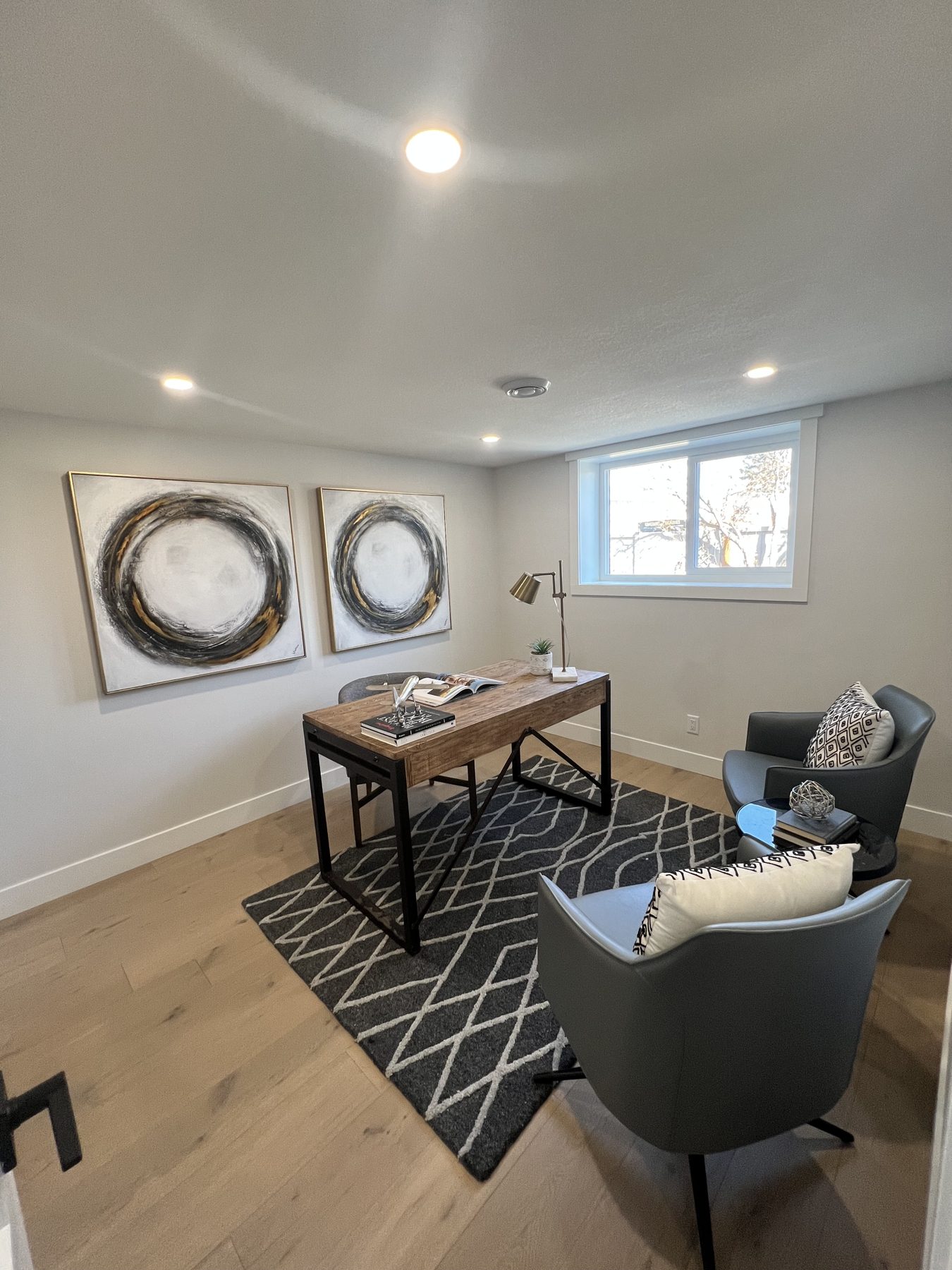 Modern office with wood desk, gray chairs, and abstract art — 720 Lake Twintree Crescent SE, Calgary