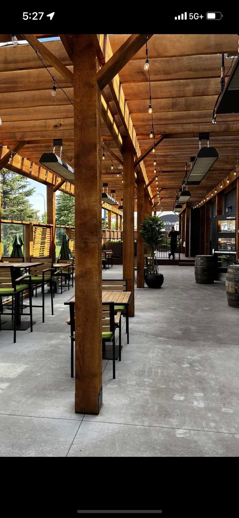 Wooden beams support open-air dining space with tables, chairs, and heaters — Blowers and Grafton (Lethbridge)