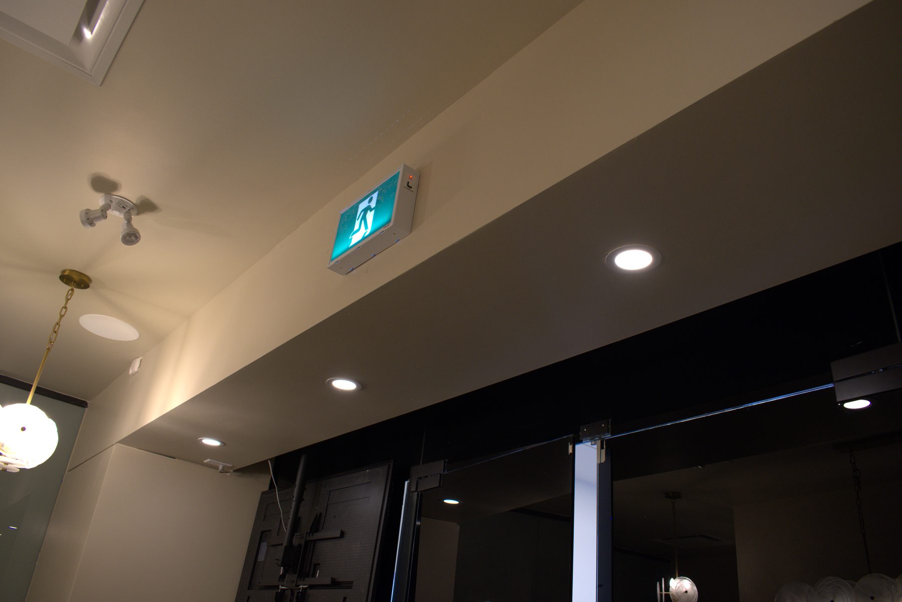Ceiling with recessed lights, emergency exit sign, and pendant light fixture — Leela Spa (Bankers Hall)