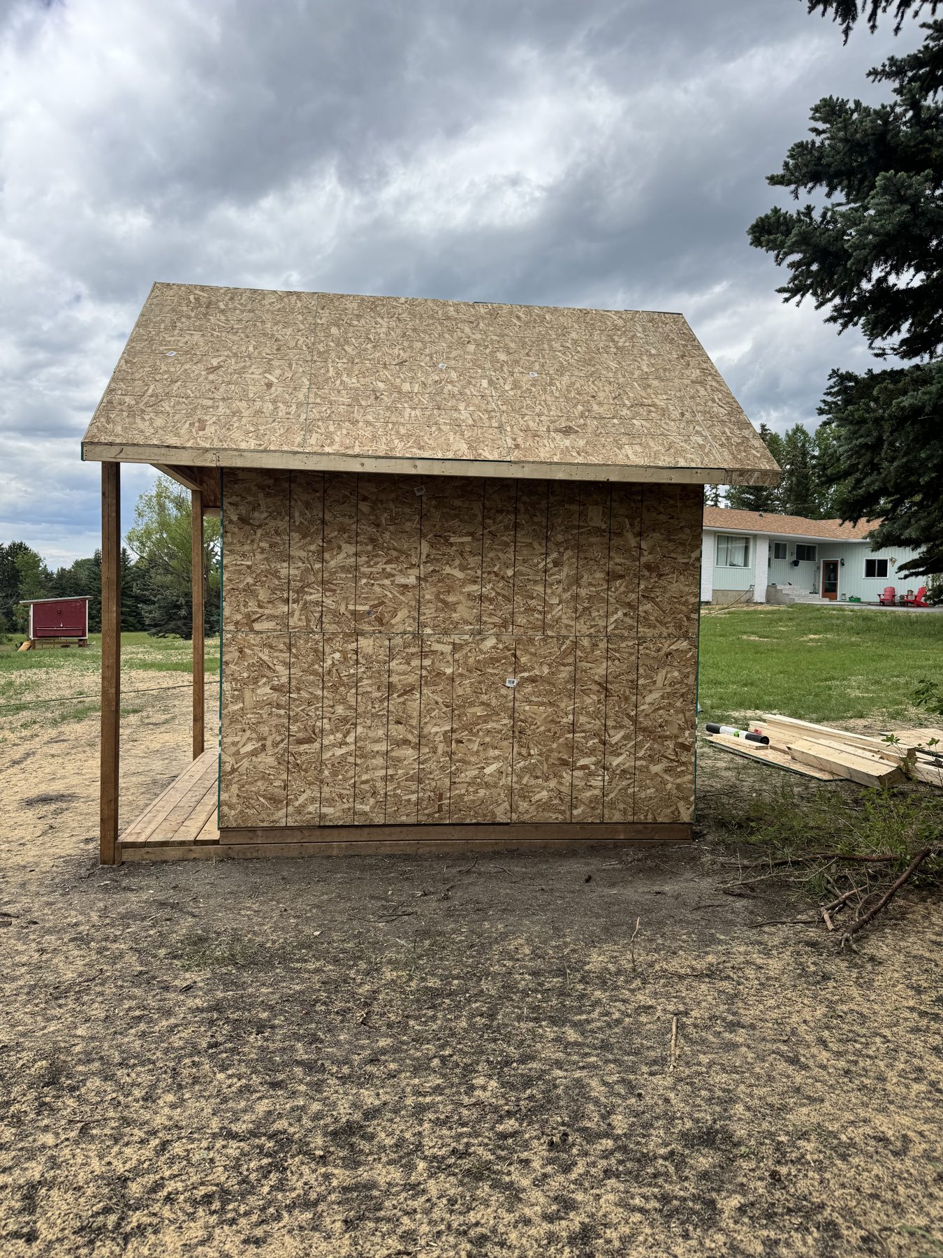 Shed under construction with OSB walls and roof sheathing, wooden porch — 101 Lariat Loop, Calgary