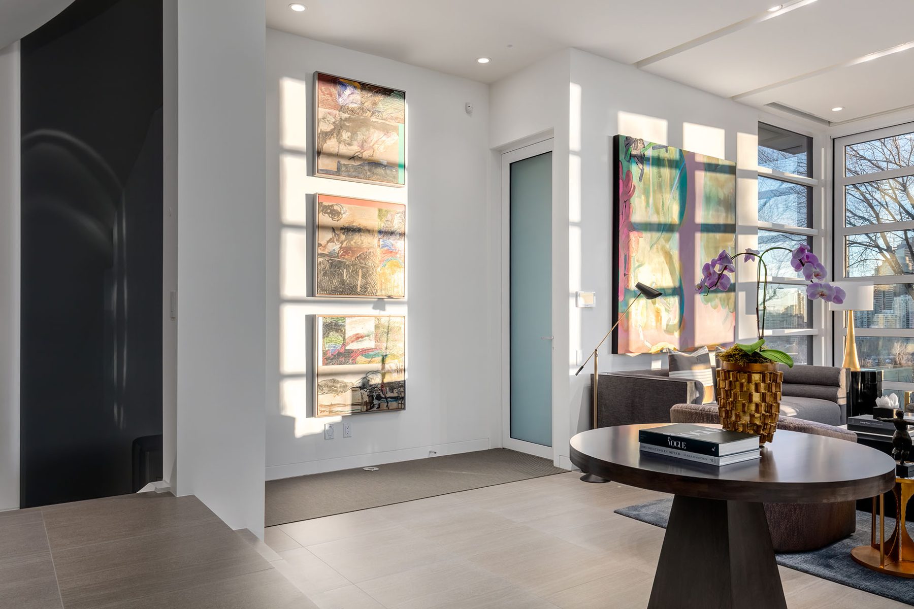 Entryway with art, frosted door, round table, and large windows — Skyline