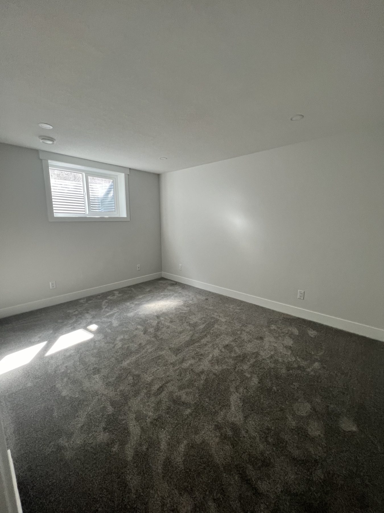 Newly carpeted room with white walls and blinds on window — 720 Lake Twintree Crescent SE, Calgary