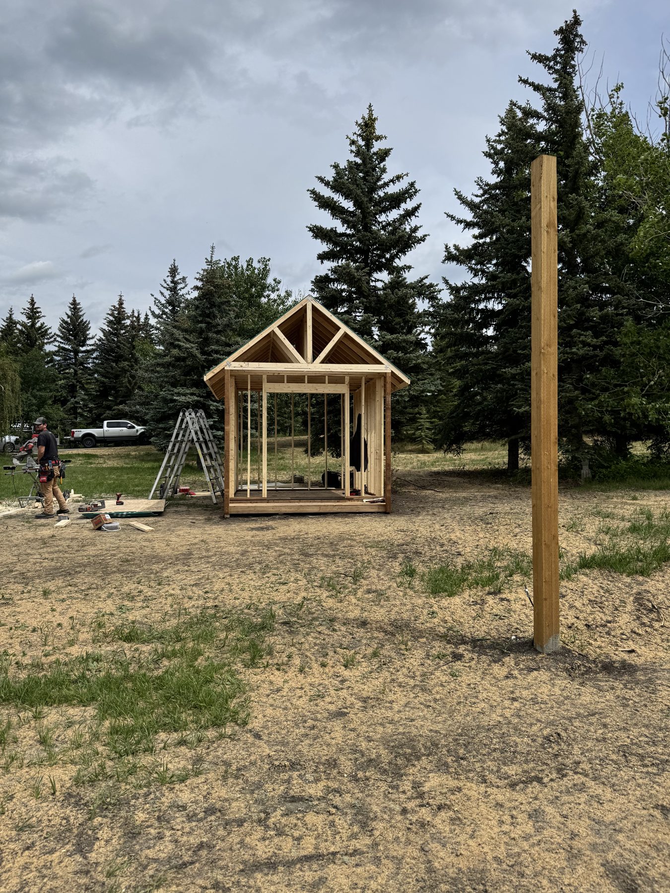 Wooden frame shed under construction with a worker nearby — 101 Lariat Loop, Calgary