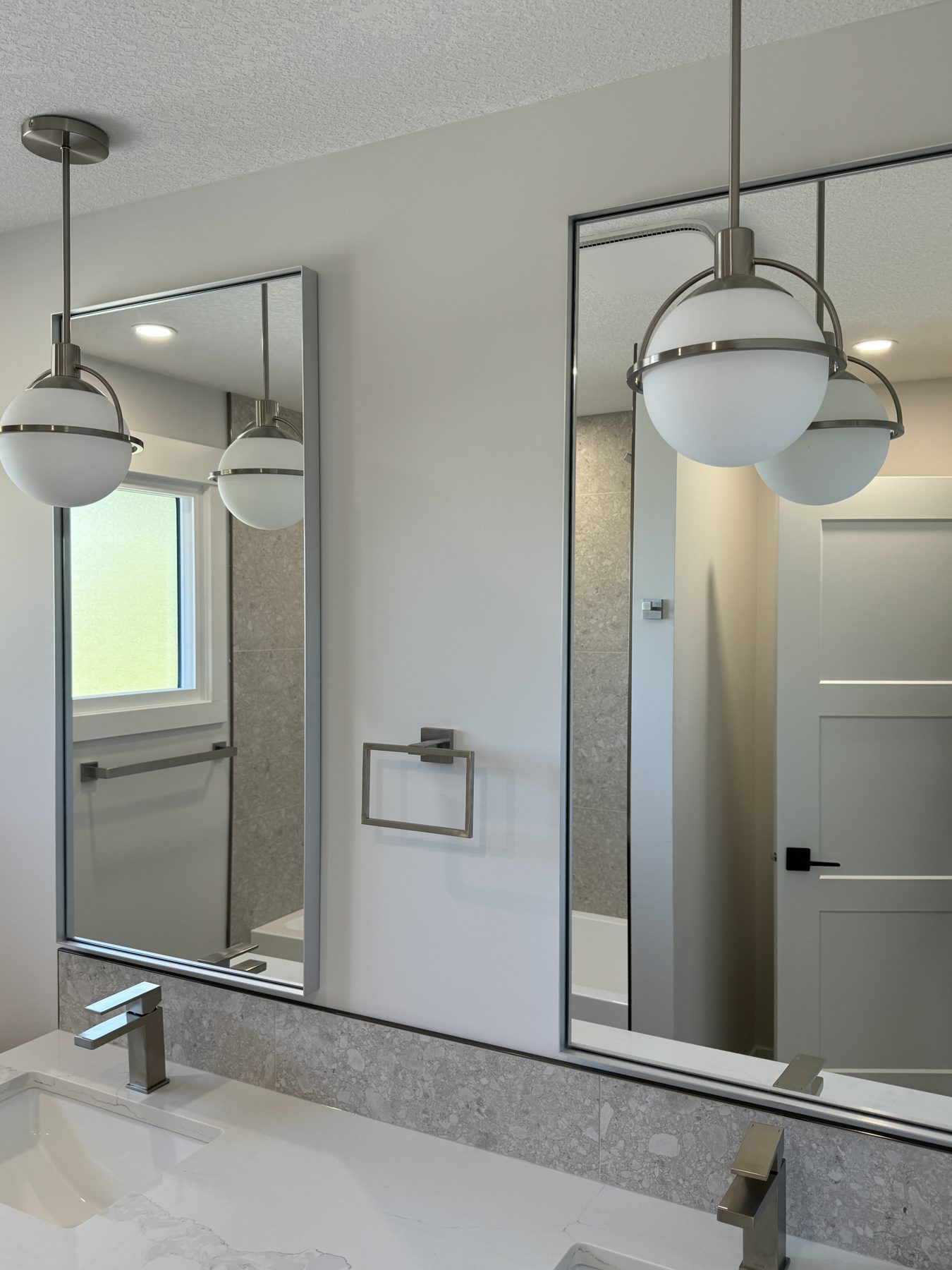 Modern bathroom with double vanity, pendant lights, and tiled shower — Lake Bonavista
