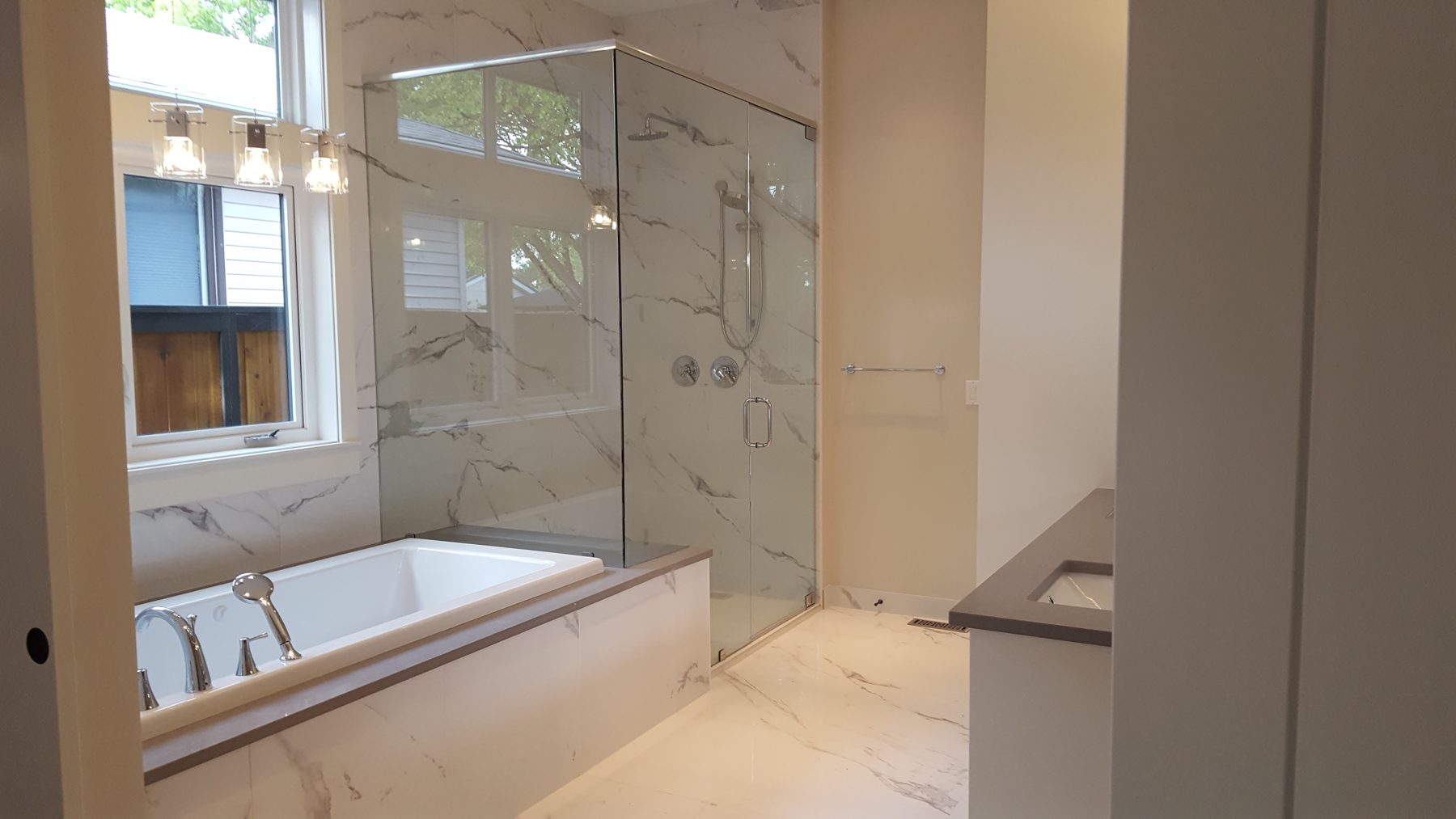 Modern bathroom renovation with marble tile, soaking tub, and glass shower enclosure — Briar Hill