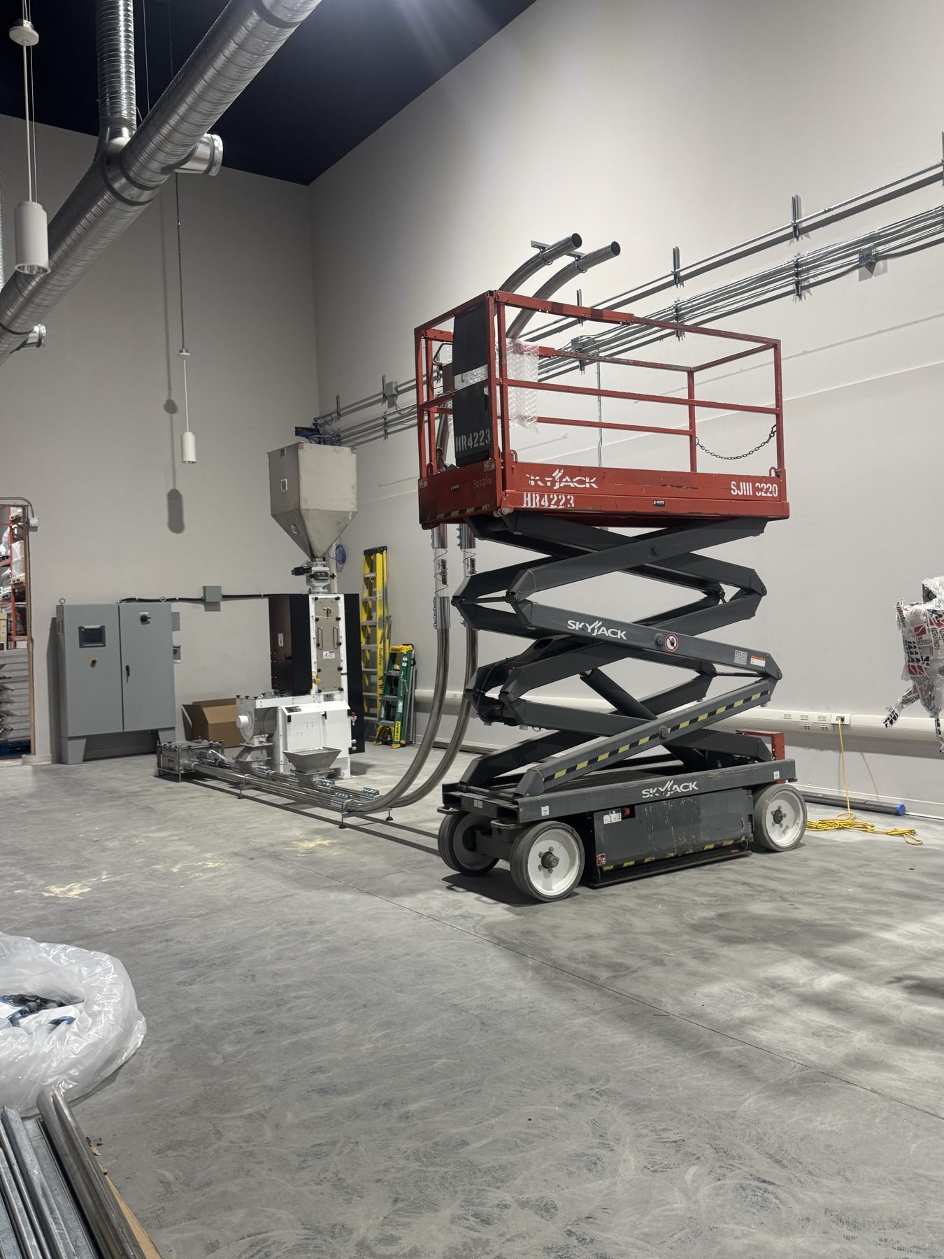 Industrial room with machinery, conduit, and a raised scissor lift — Eight Ounce Coffee
