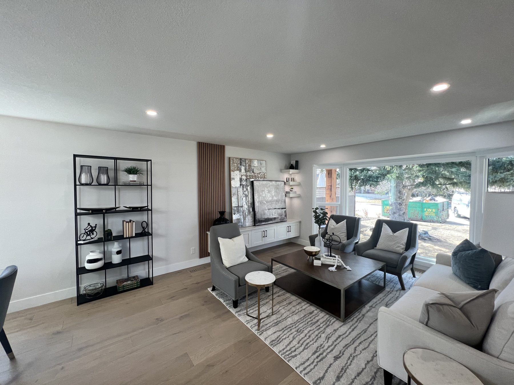 Modern living room with gray furniture, white sofa, and wood floors — 720 Lake Twintree Crescent SE, Calgary