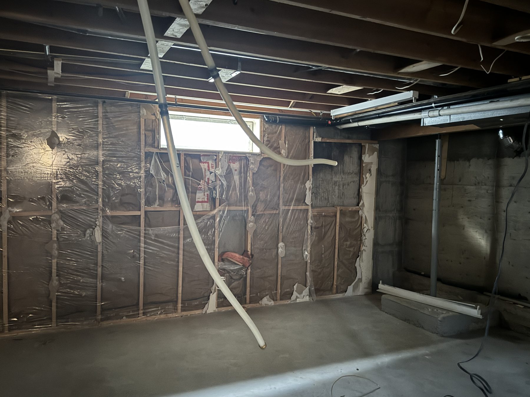 Unfinished basement walls with insulation and exposed pipes, undergoing renovation — 188 Lake Adams Crescent SE, Calgary