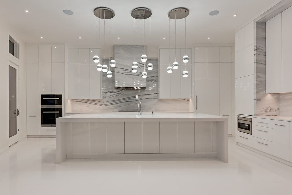 Modern white kitchen with marble backsplash, island, and pendant lights — Blanc de Blanc
