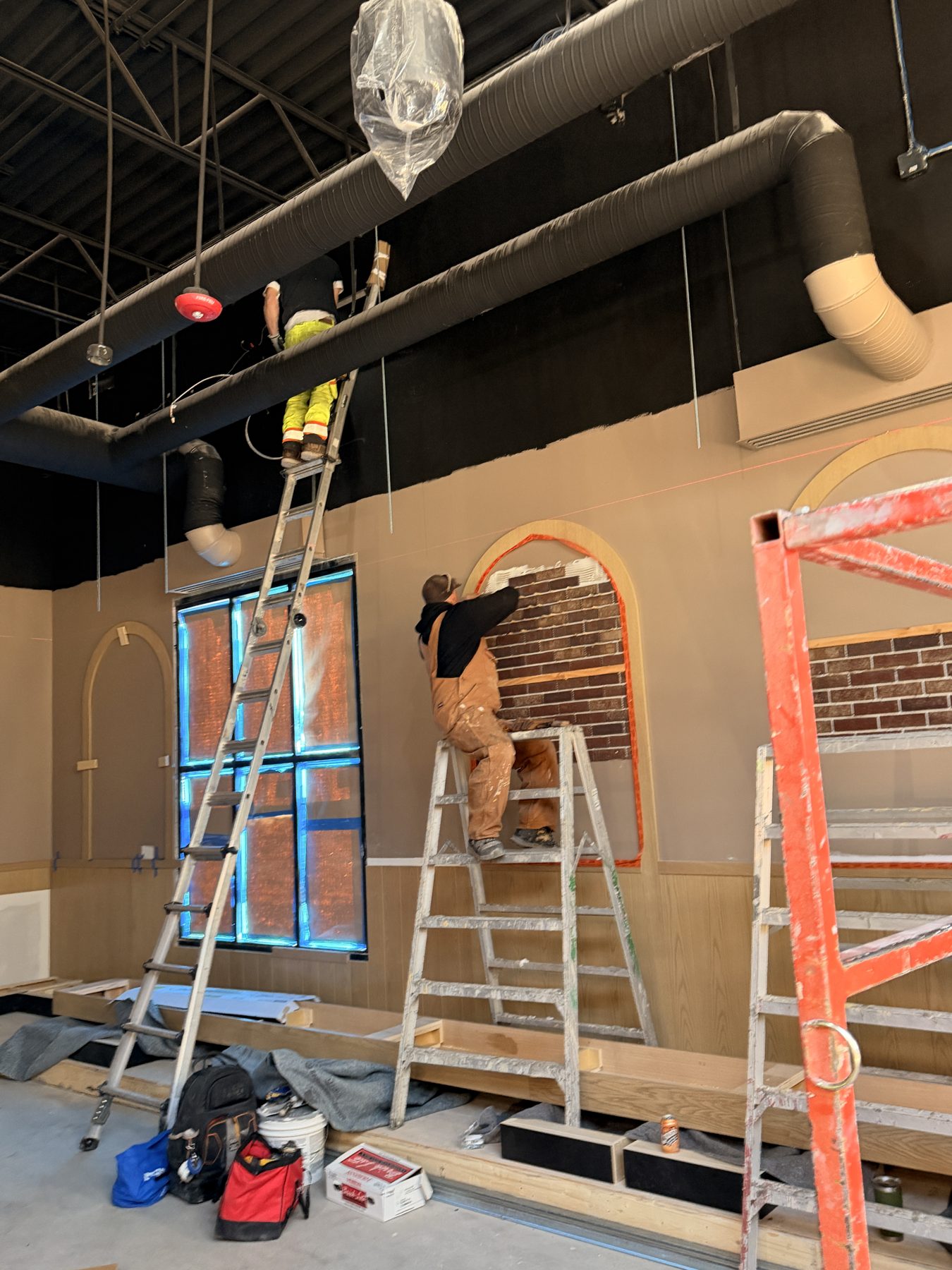 Workers install brick veneer around an arched window opening — Blowers and Grafton (Red Deer)