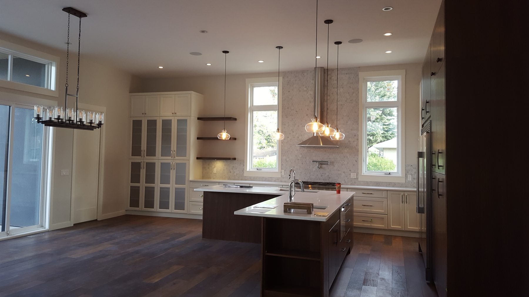 Modern kitchen island with waterfall countertop, cabinets, and pendant lights — Briar Hill by Onsite Contracting Services