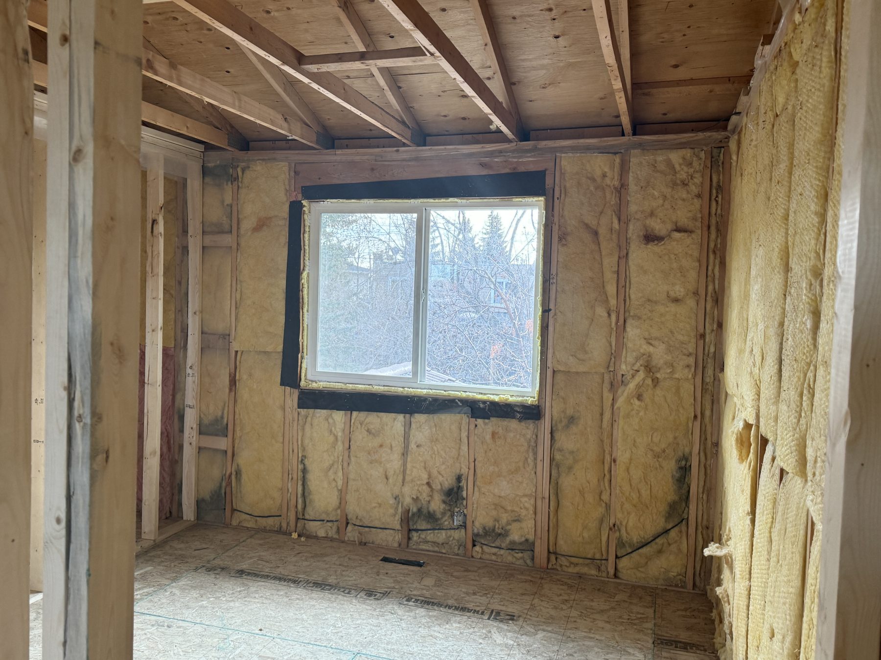 Construction site with exposed insulation, framing, and window in room — 188 Lake Adams Crescent SE, Calgary