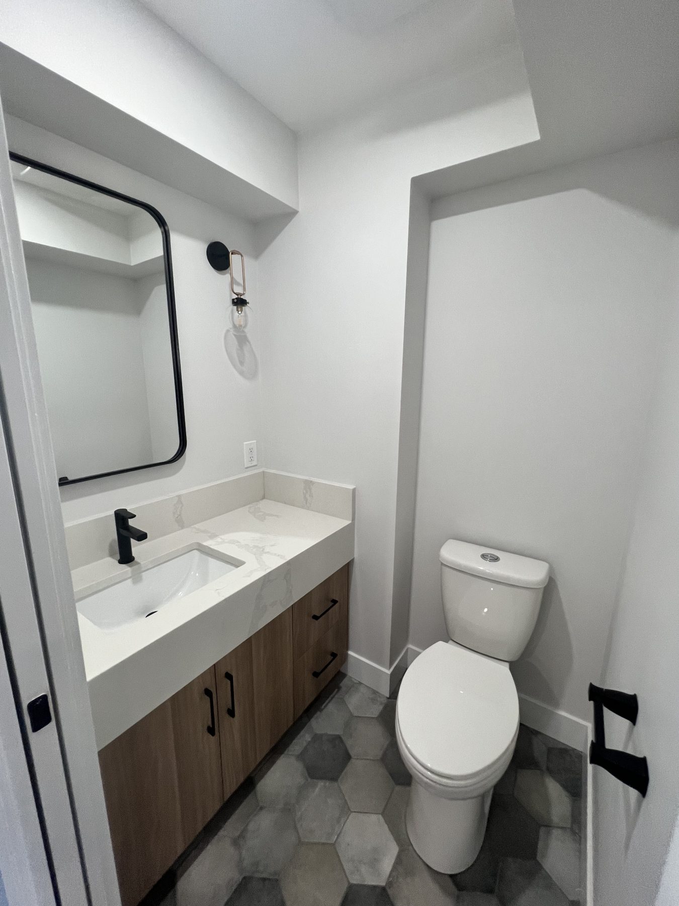 Modern bathroom renovation with hexagon tiles, wood vanity, and new fixtures — 720 Lake Twintree Crescent SE, Calgary
