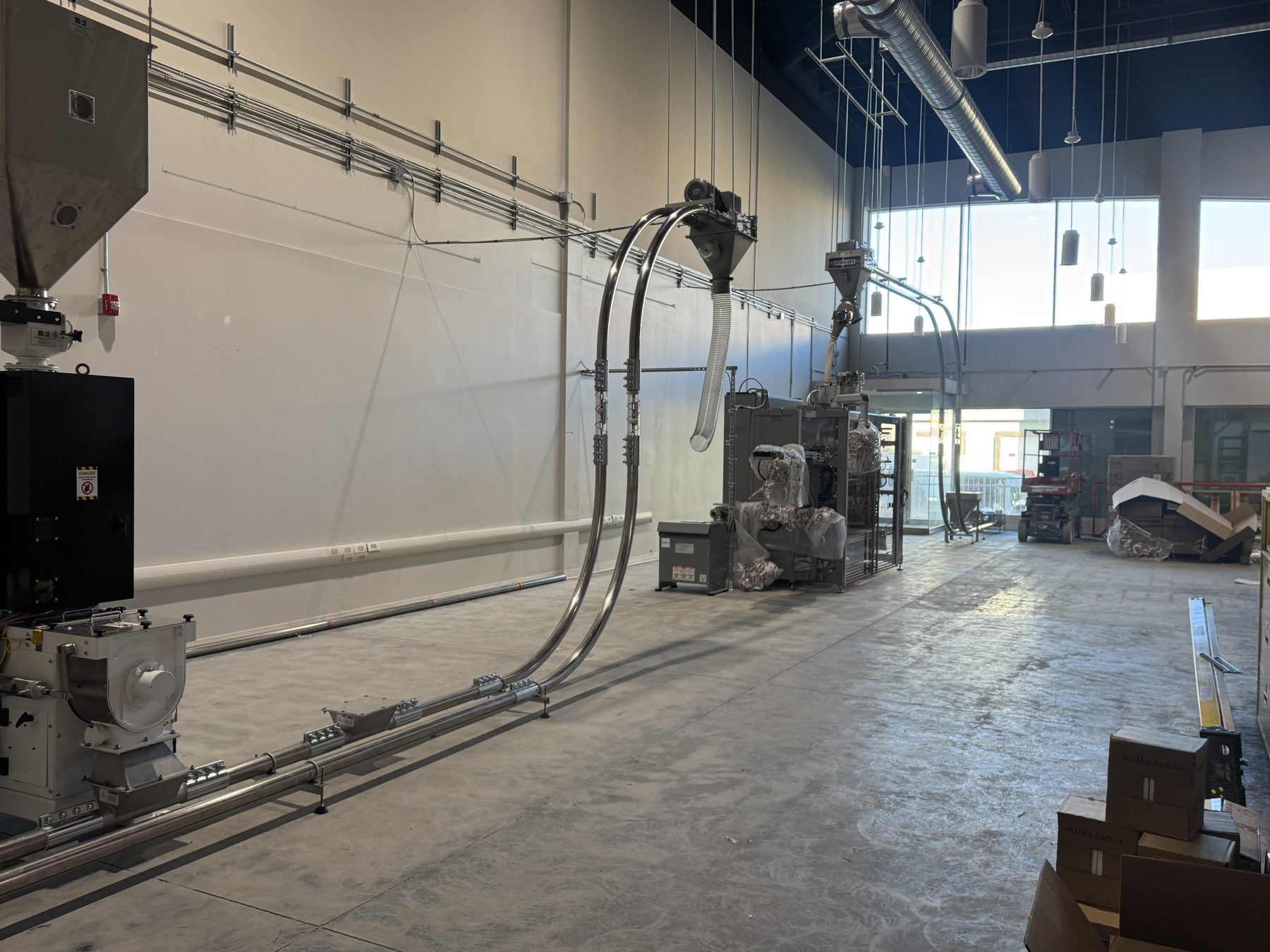 Industrial packaging machinery installed in a large unfinished space — Eight Ounce Coffee