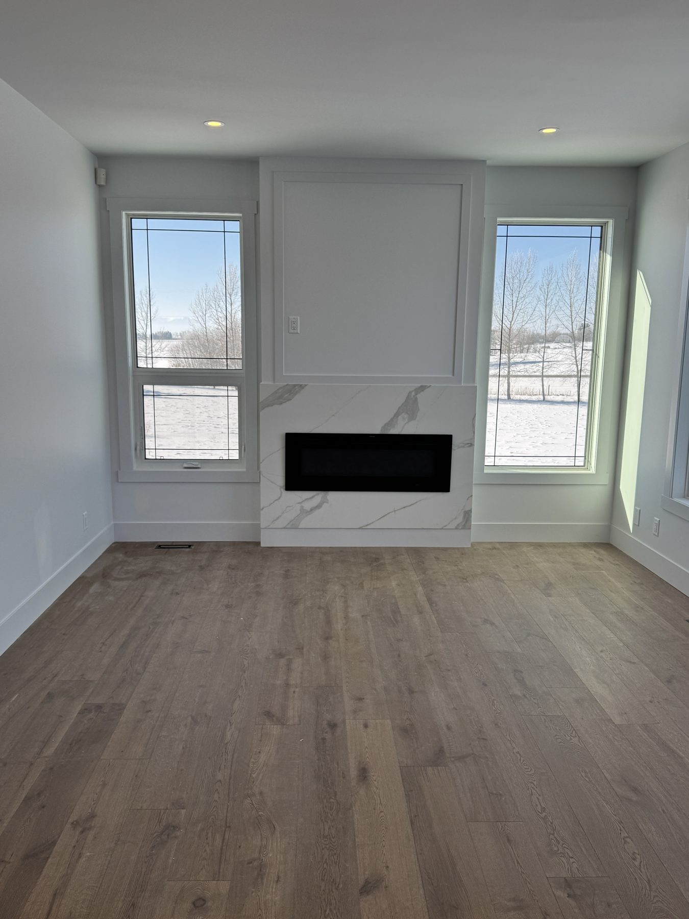 Living room with new fireplace, marble surround, and wood flooring — 14 Lochend Drive, Cochrane