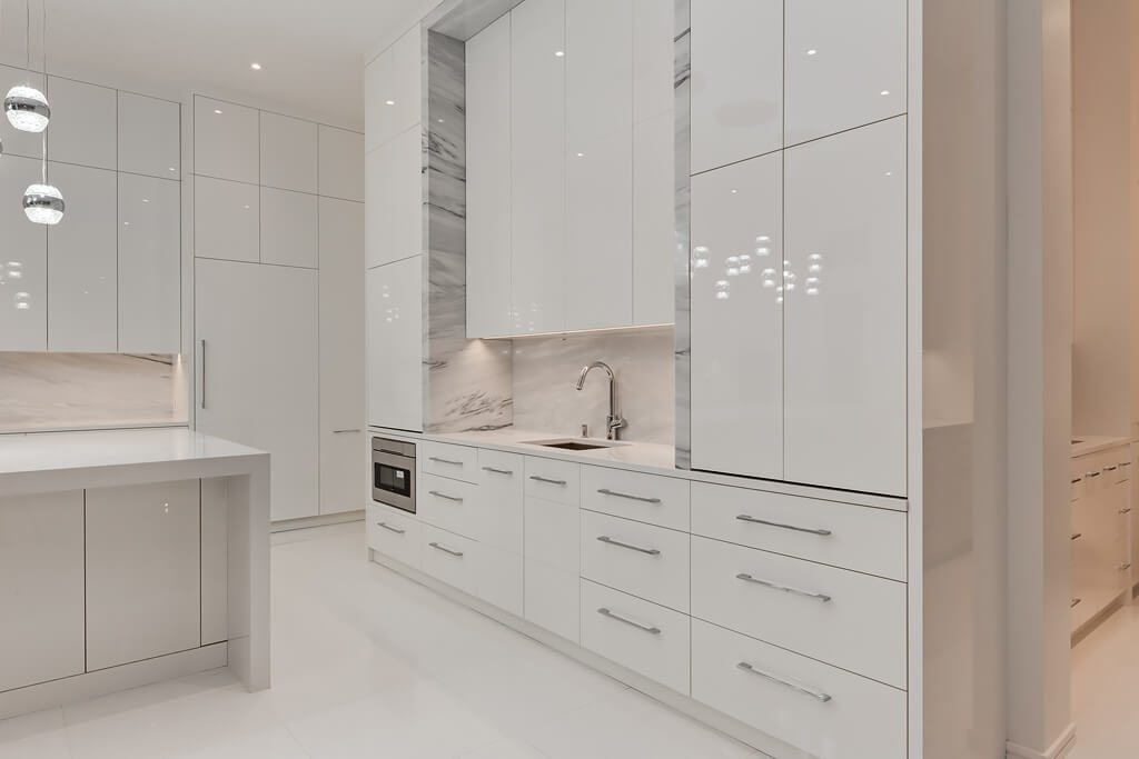 Modern white kitchen with marble backsplash and island, minimal fixtures — Blanc de Blanc