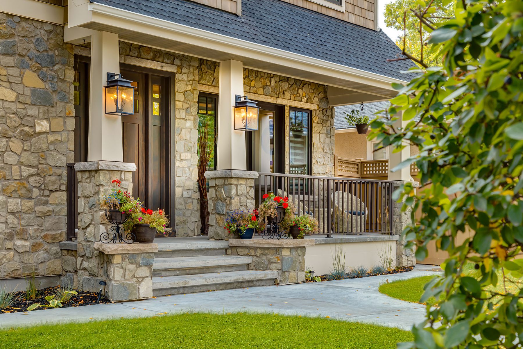 Stone facade with covered porch, stairs, and modern entryway lights — Artista