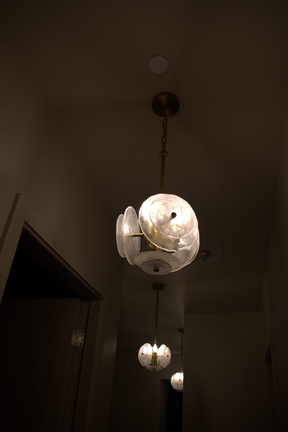 Hallway with two glass disk pendant lights and one ceiling fixture — Leela Spa (Bankers Hall)