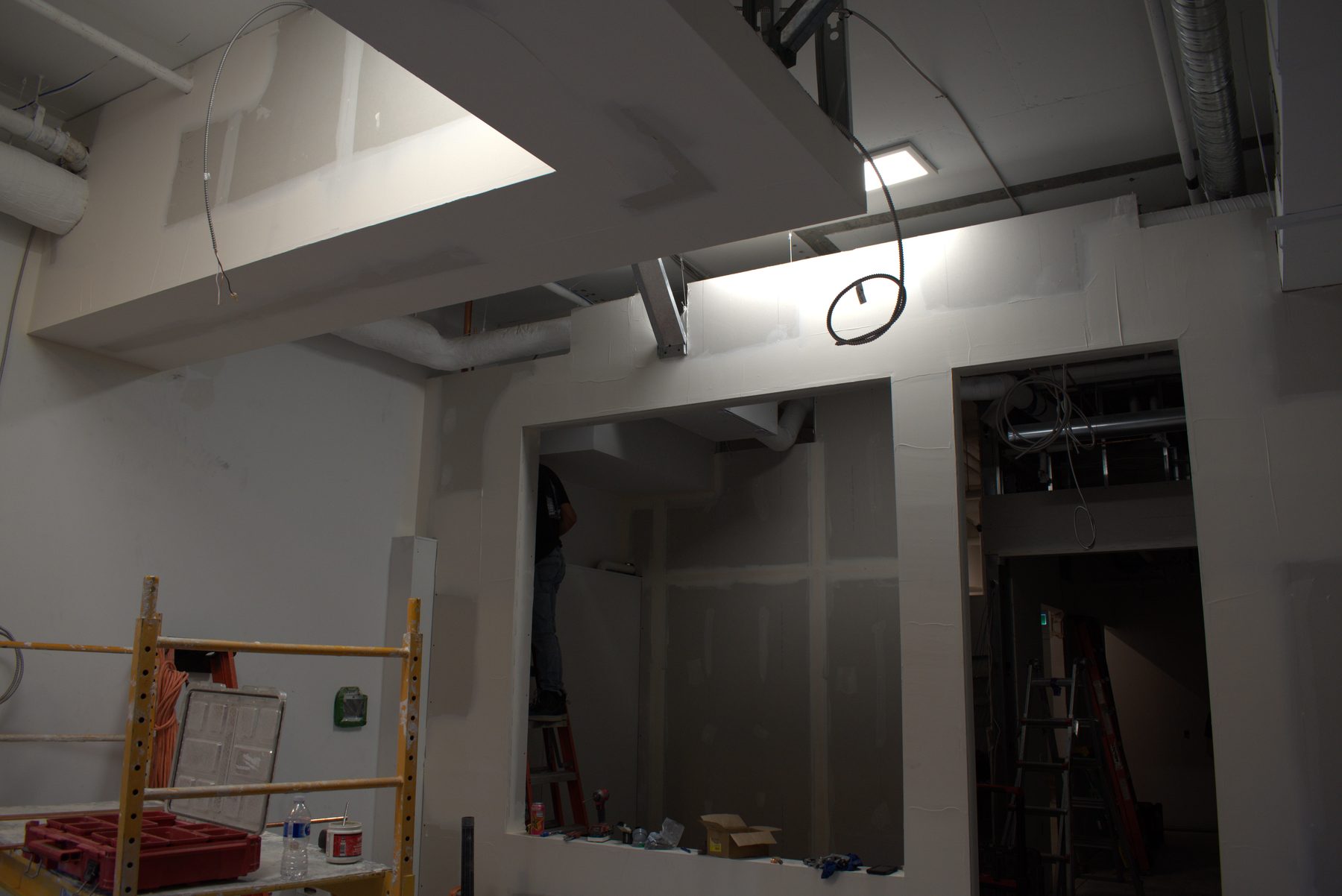 Drywall installation with scaffolding, tools, and exposed ductwork — Big Buns (Bowness)