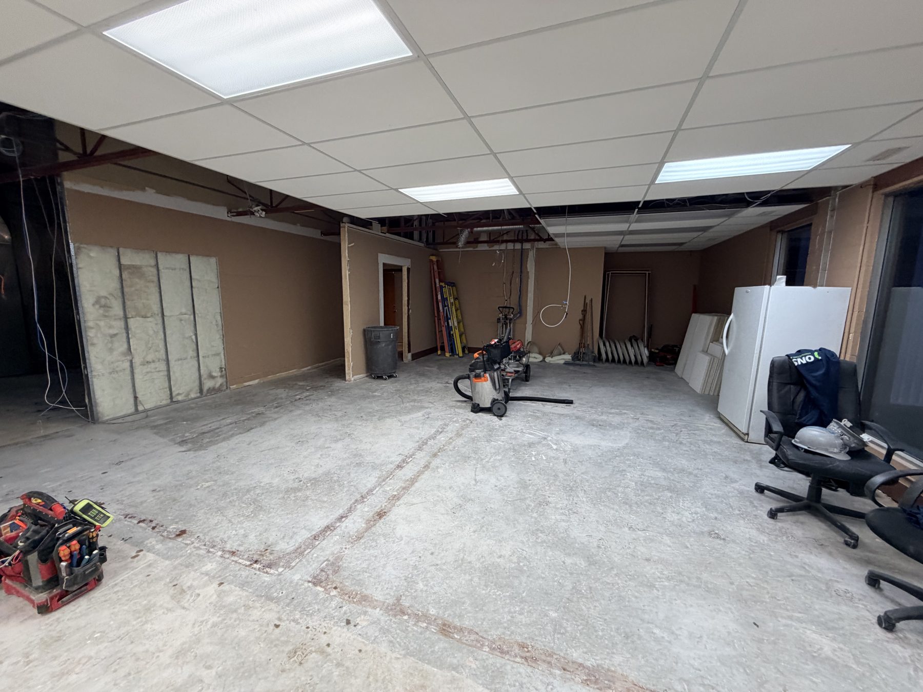 Office renovation with drywall, tools, and appliances on a concrete floor — The Barron Venue