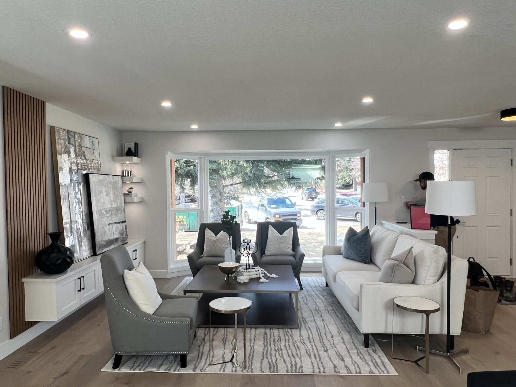 Living room with modern furnishings, wood slat wall, and artwork — 720 Lake Twintree Crescent SE, Calgary