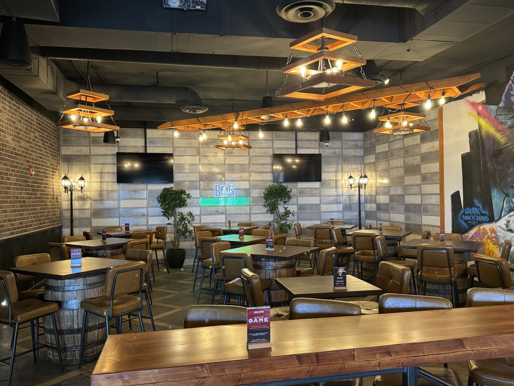 Restaurant dining area with barrel tables, leather chairs, and rustic lighting — Blowers and Grafton (Shawnessy) by Onsite Contracting Services