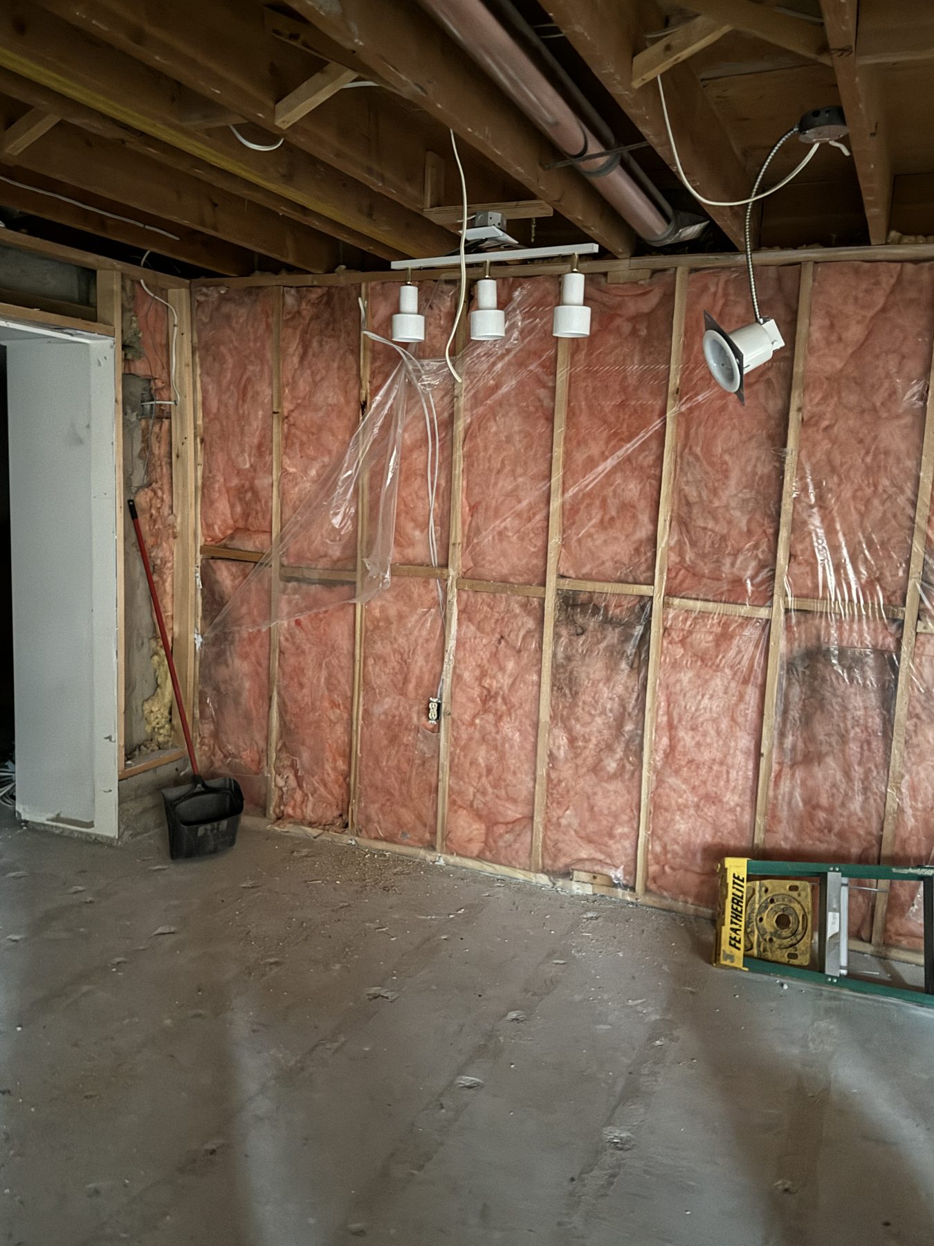 Basement framing with pink insulation and plastic sheeting, unfinished room — 188 Lake Adams Crescent SE, Calgary