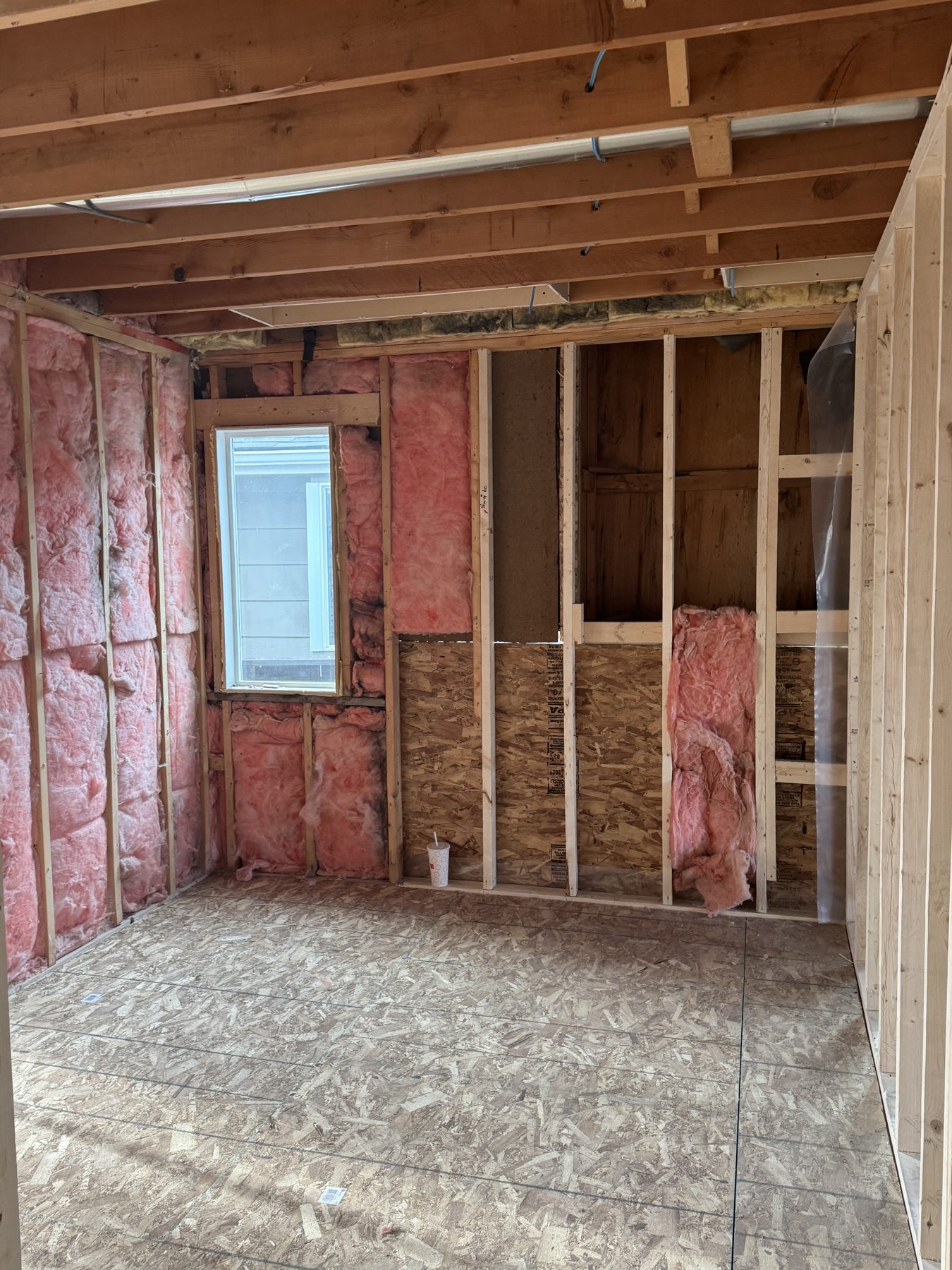 Room framing with insulation, unfinished wood floors, and a window — 188 Lake Adams Crescent SE, Calgary