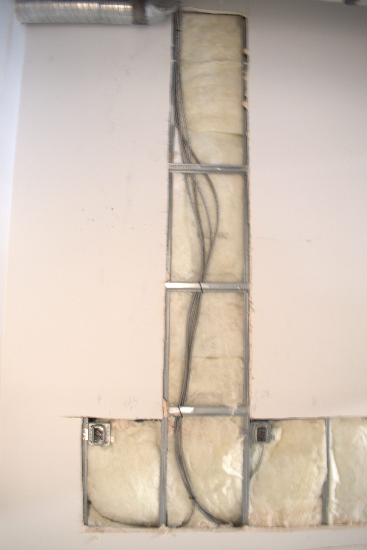 Wall cavity exposed, showing insulation, metal studs, and wiring — Big Buns (Bowness)