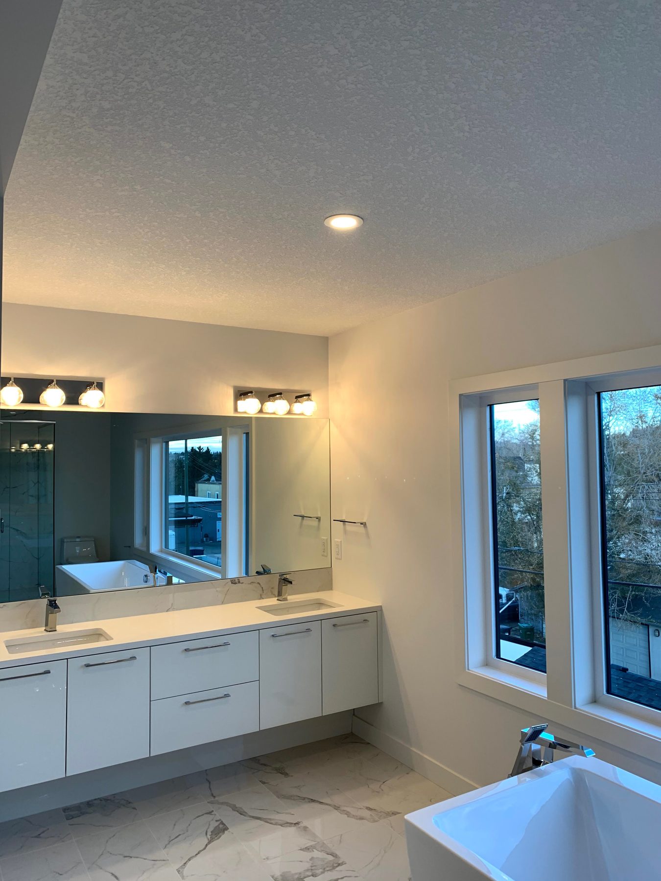 Modern bathroom with white vanity, soaking tub, and marble tile flooring — Lake Bonavista