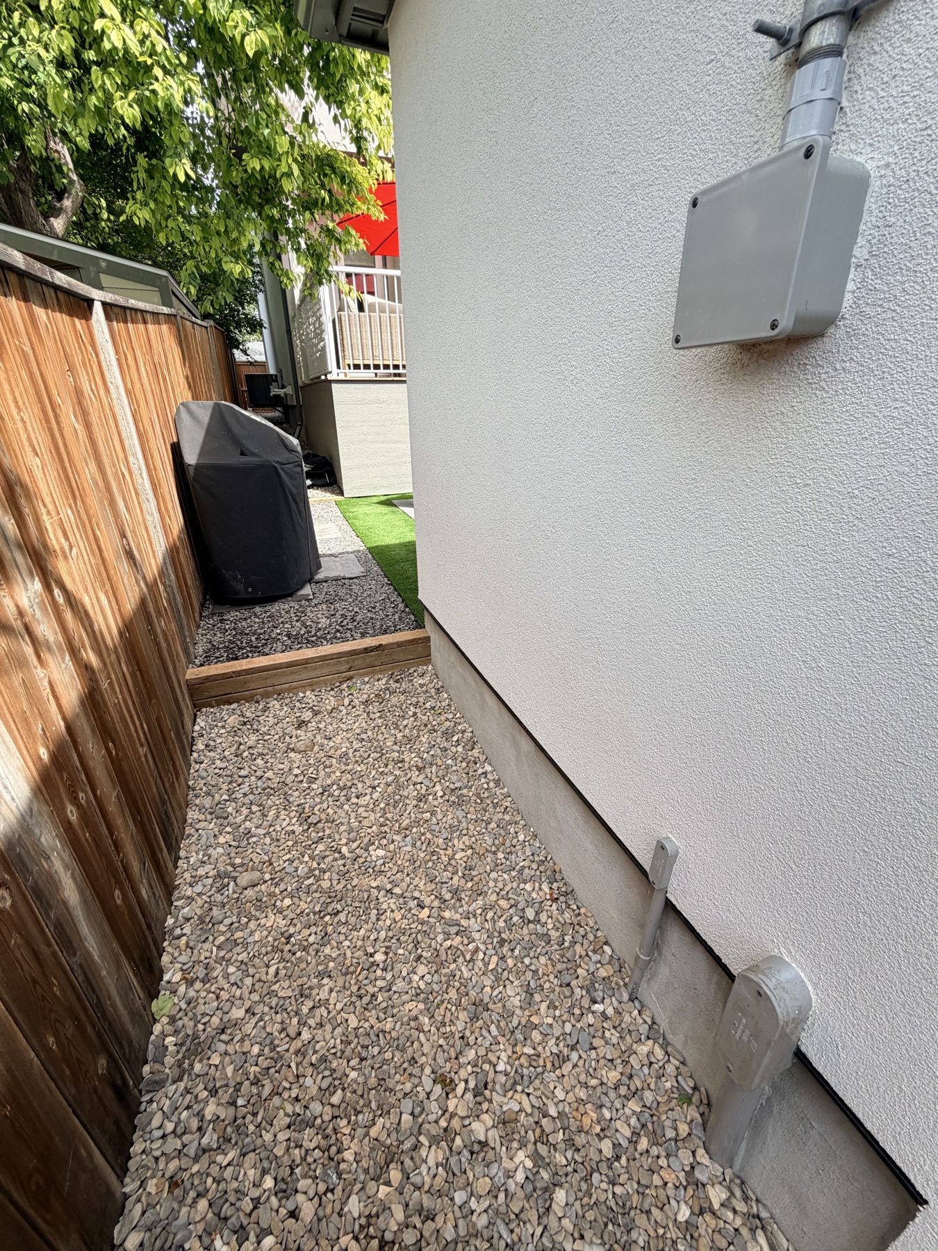 Exterior wall with electrical box, gravel path, and wooden fence — 3505 41 Street SW, Calgary