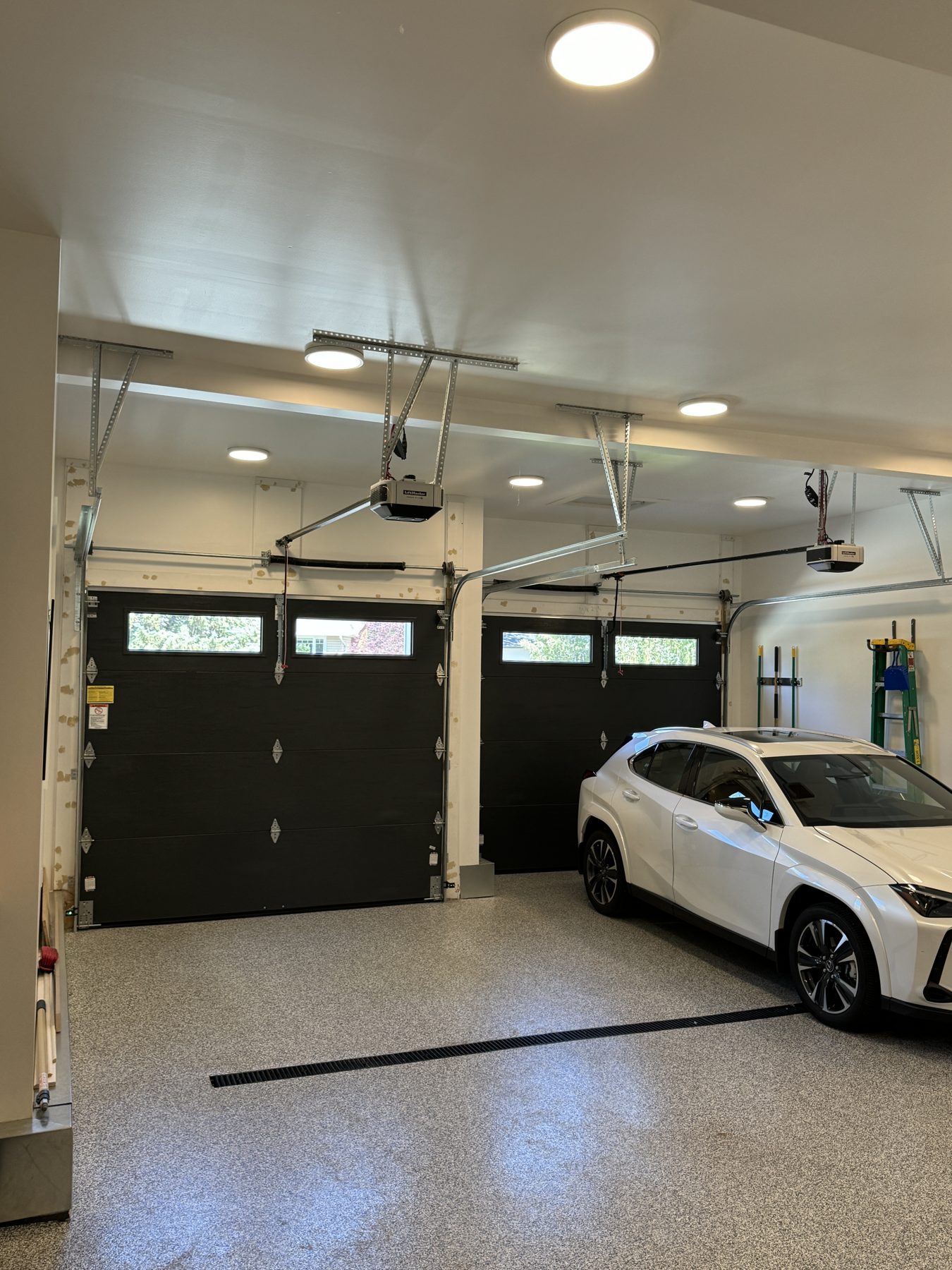 Newly installed garage doors, openers, and epoxy flooring with car — 18 Varsplain Place Northwest