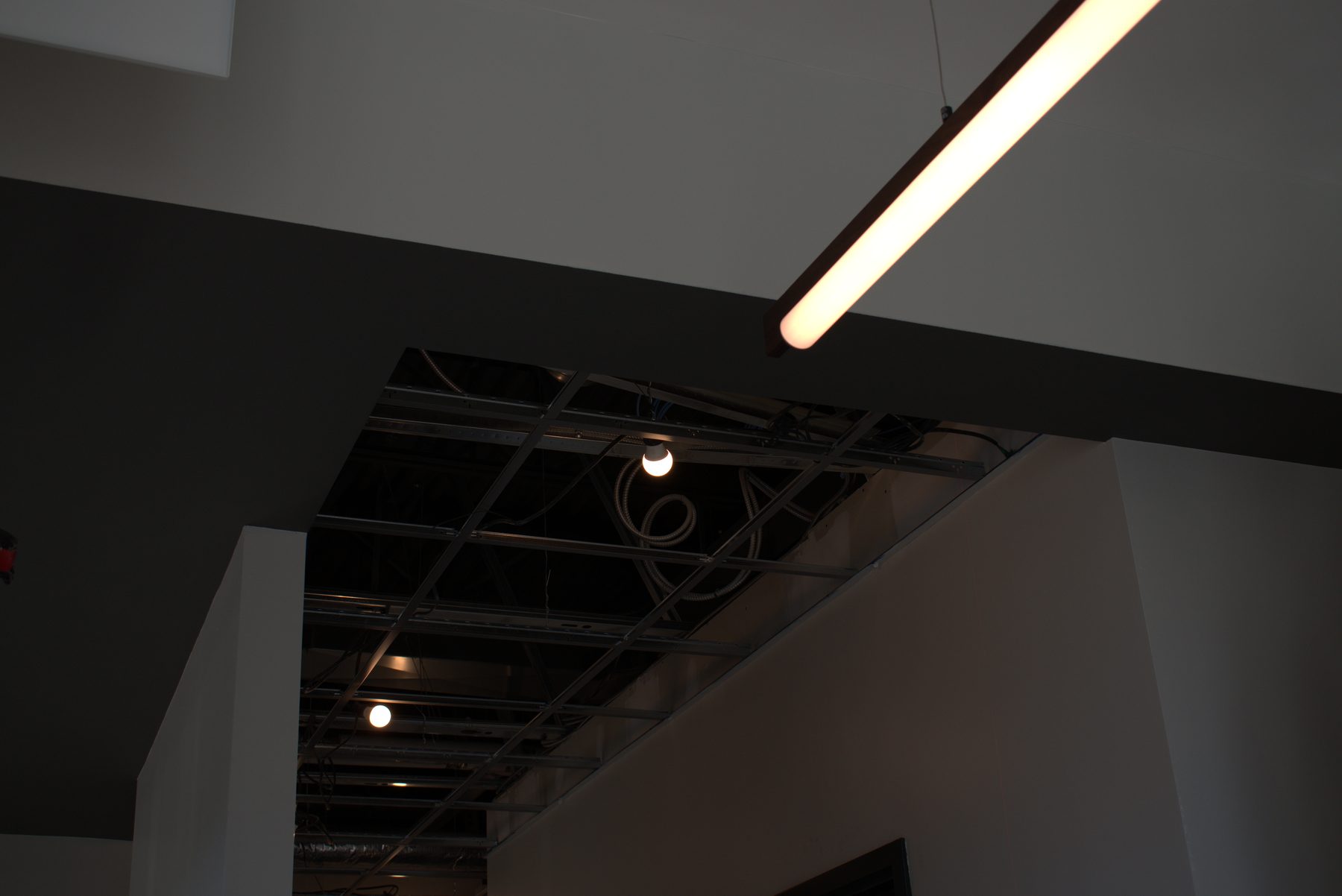 Exposed ceiling grid, wiring, and fixtures during renovation — ONE8T (West District)