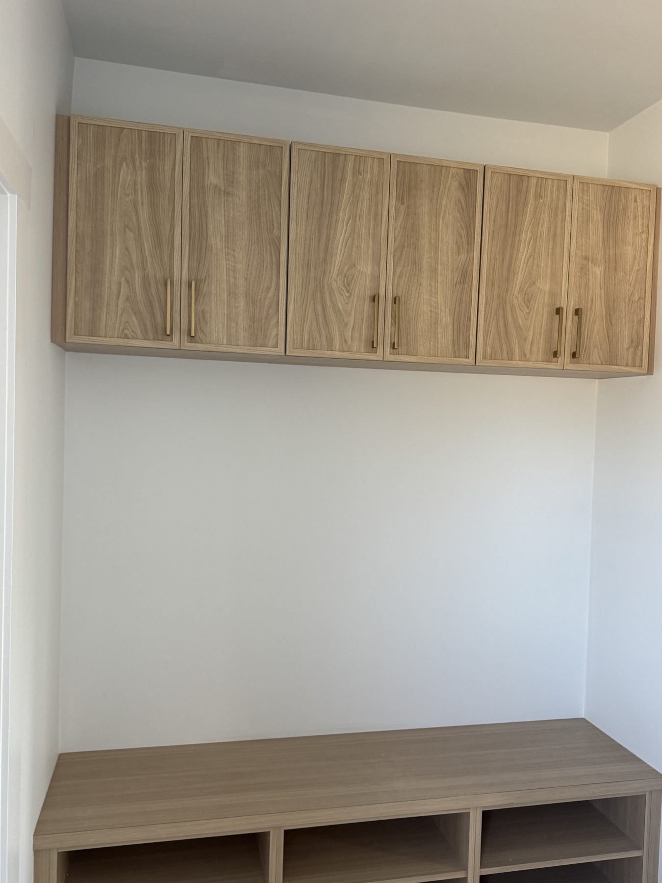 Newly installed wood cabinets with brass handles above a bench — 14 Lochend Drive, Cochrane