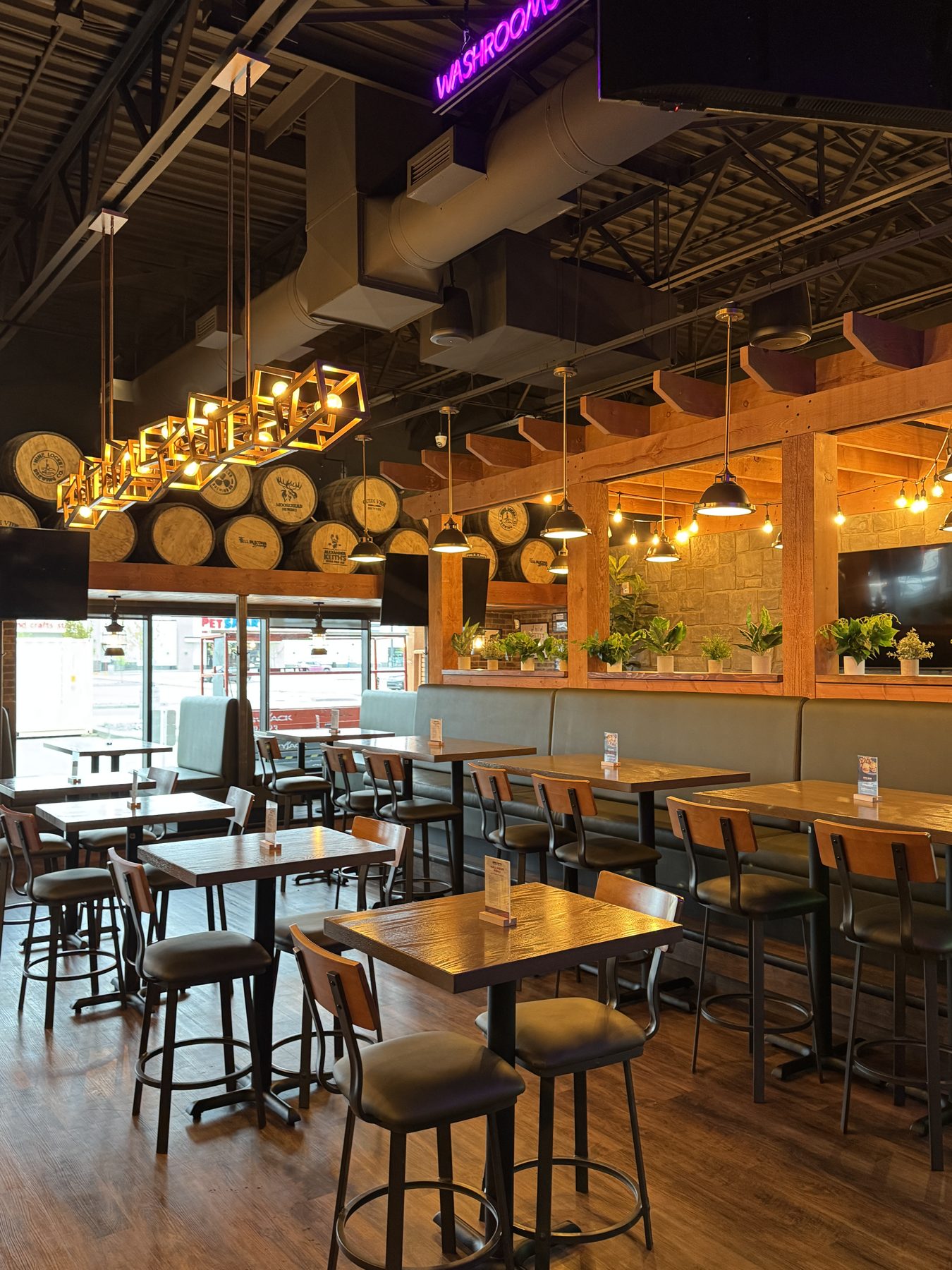 Restaurant dining area with wooden tables, bar stools, and barrel decor — Blowers and Grafton (Lloydminster) by Onsite Contracting Services
