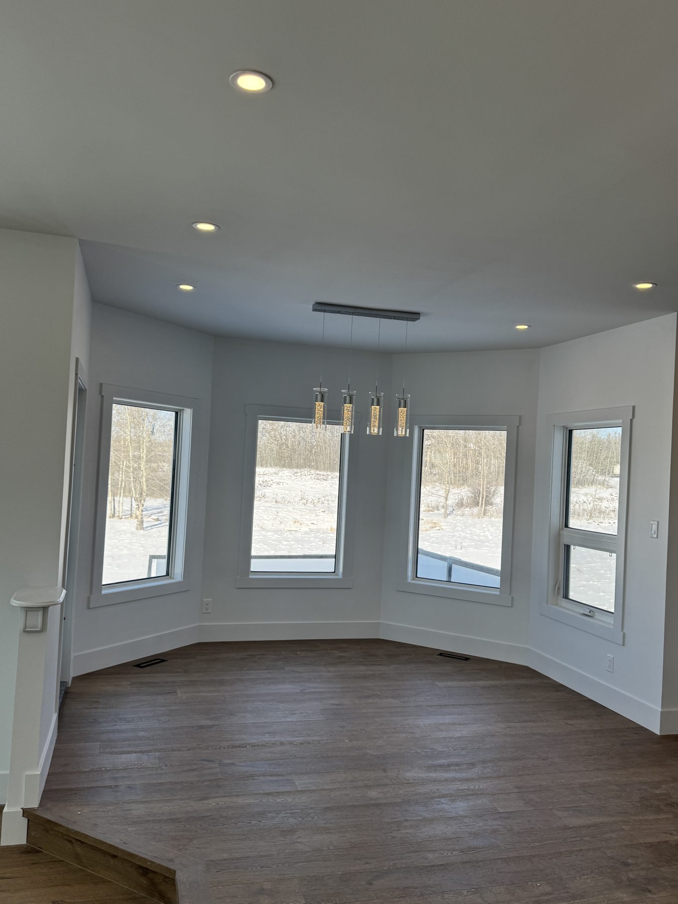 New room with wood floor, large windows, and modern light fixture — 14 Lochend Drive, Cochrane