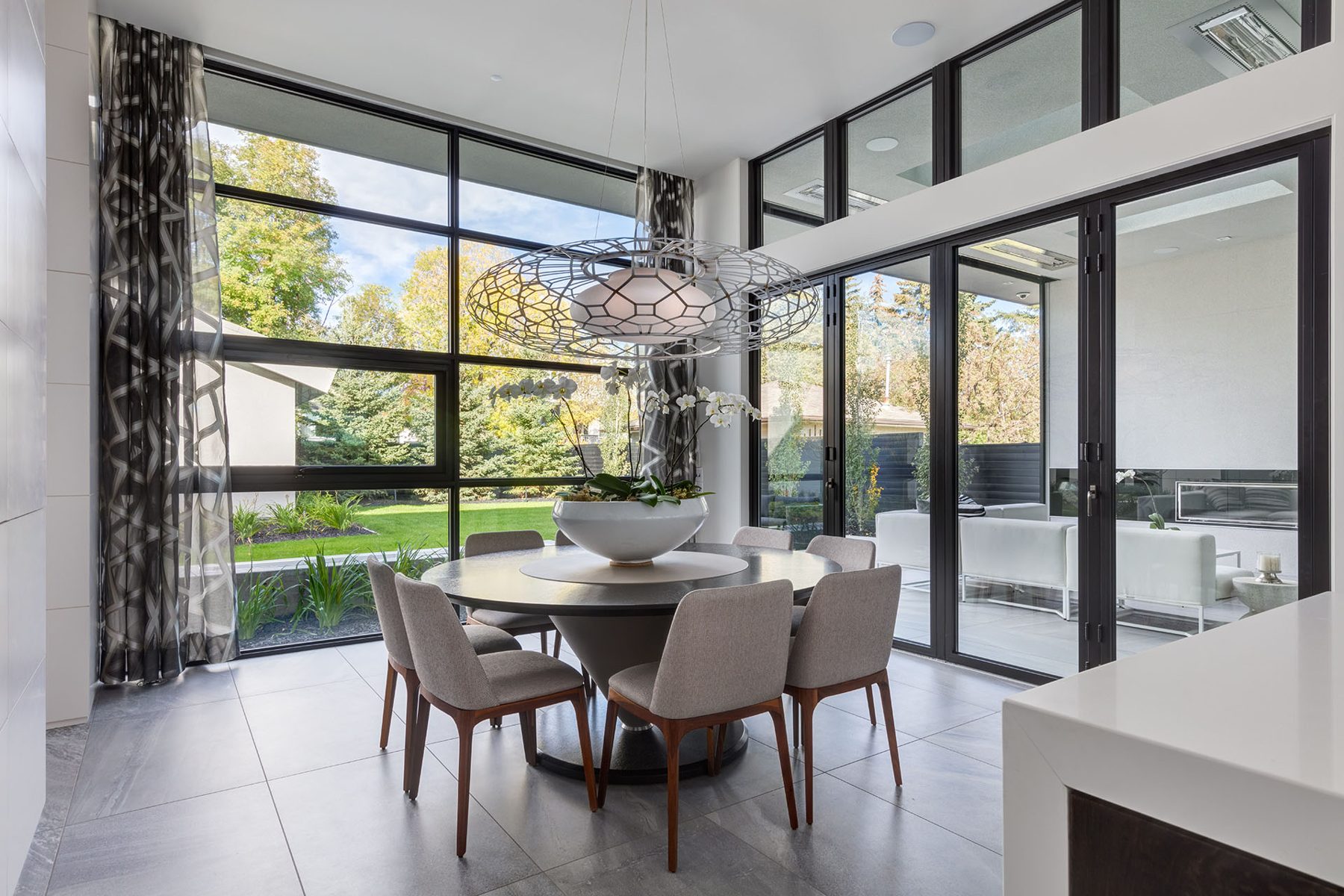 Modern dining room with large windows, gray chairs, and a sculptural pendant light — Infinity