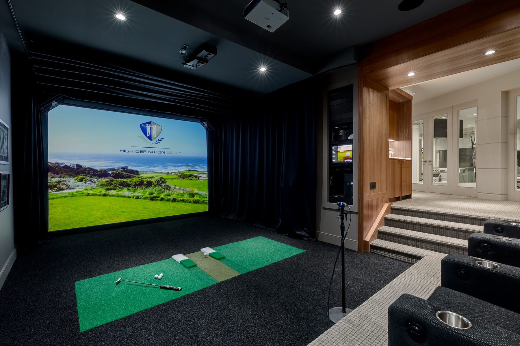 Golf simulator room with screen, mats, clubs, and tiered seating — Evolution