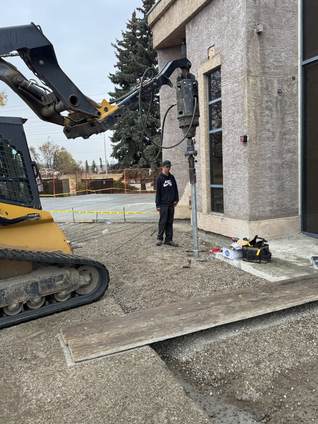 Skid steer loader and hydraulic hammer install support pole near building — Blowers and Grafton (Red Deer)